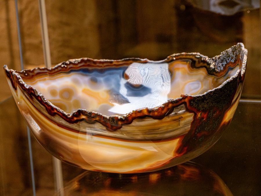 Schale aus Achat mit unregelmäßig gezacktem Rand und mehrfarbiger, gestreifter Maserung in Braun-, Blau- und Beigetönen, ausgestellt in der Sonderausstellung.